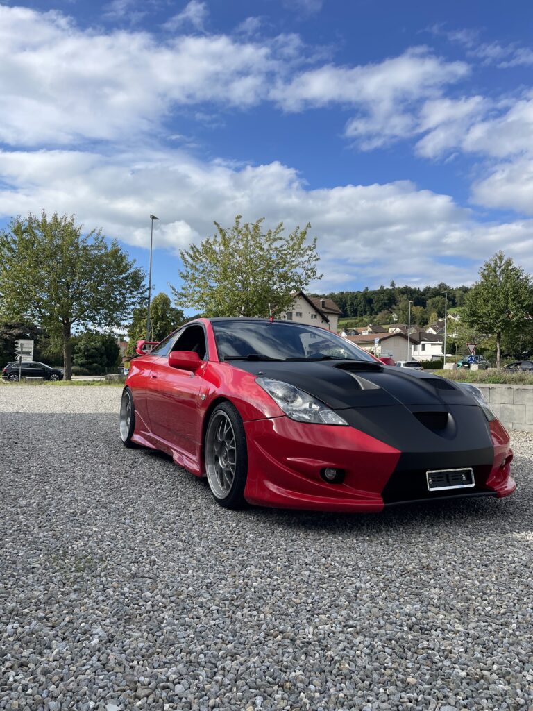 Roter Sportwagen mit schwarzer Front-Teilfolierung auf Kiesplatz