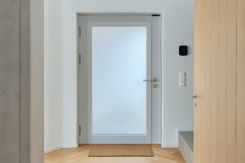 milchglas-innentuer-flur-sichtschutz-parkett-hero.jpg Zeitloser Flur mit blickdichter Milchglas-Innentür, klaren Linien, Schalterfeld und warmem Holzparkett.